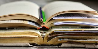 Bücher Aufgeschlagene Bücher und Stifte